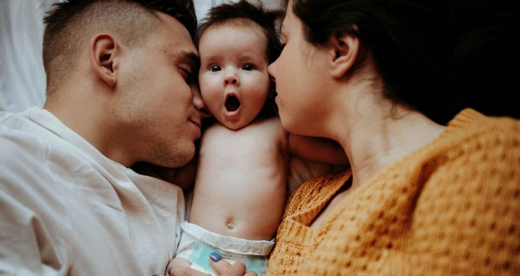 Intended parents who received financial assistance for surrogacy snuggling with their newborn
